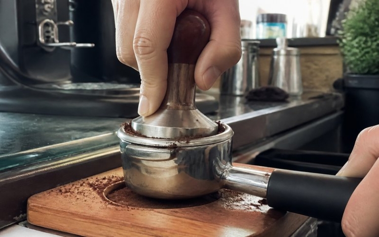 Tamper presst Kaffeemehl im Siebträger
