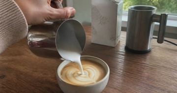 Aufgeschäumte Pflanzenmilch wird in den Kaffee gegossen